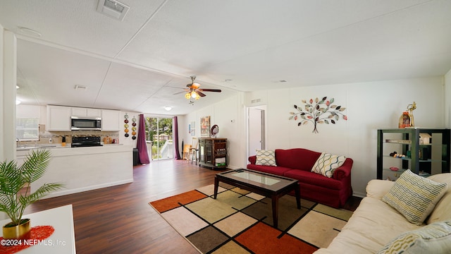 living room with ceiling fan, a textured ceiling, and dark hardwood / wood-style floors