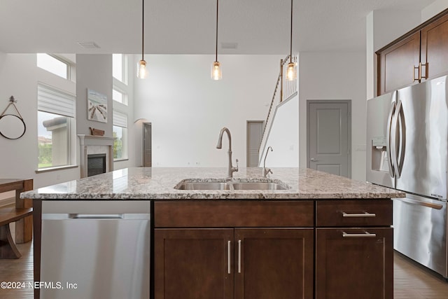 kitchen featuring sink, a kitchen island with sink, light hardwood / wood-style flooring, stainless steel appliances, and light stone countertops