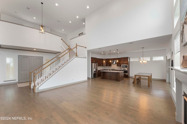 living room with a towering ceiling, dark wood-type flooring, an inviting chandelier, and sink