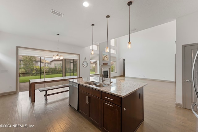 kitchen with light stone counters, light hardwood / wood-style flooring, stainless steel dishwasher, and a healthy amount of sunlight