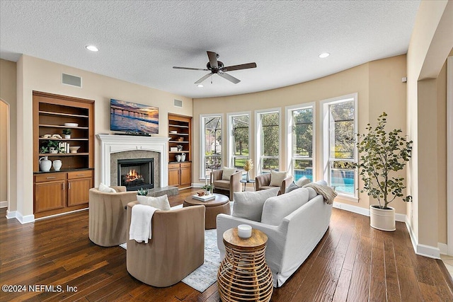 living room featuring ceiling fan, built in features, a textured ceiling, and dark hardwood / wood-style flooring