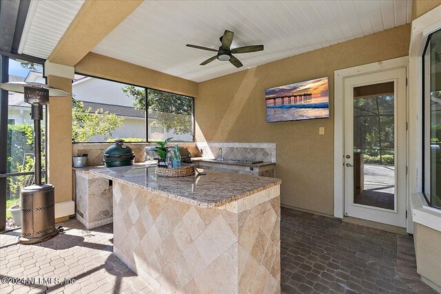 view of patio / terrace featuring area for grilling, glass enclosure, and ceiling fan