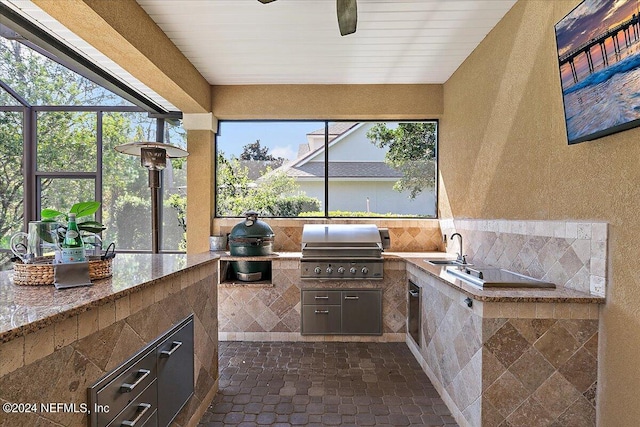 view of patio with an outdoor kitchen, sink, grilling area, and glass enclosure