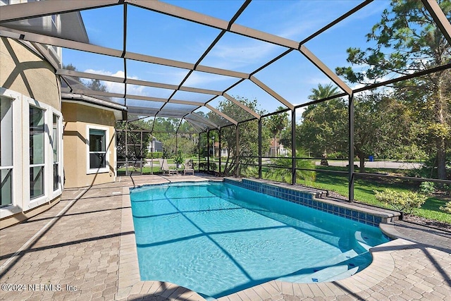 view of pool featuring a patio, a lawn, and glass enclosure