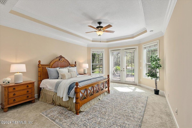 bedroom featuring multiple windows, access to exterior, ceiling fan, and a raised ceiling