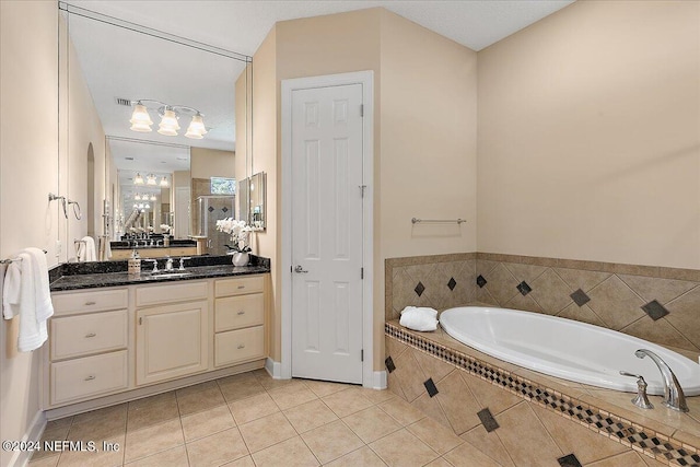 bathroom with vanity, a textured ceiling, a relaxing tiled tub, and tile patterned floors