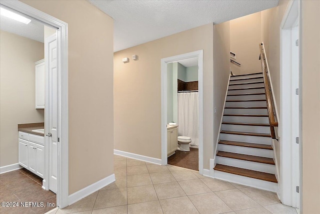 staircase featuring tile patterned floors and a textured ceiling