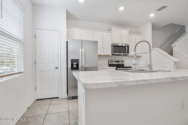 kitchen with white cabinetry, appliances with stainless steel finishes, sink, and an island with sink