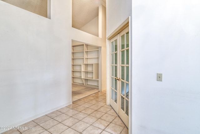 tiled empty room featuring high vaulted ceiling and a textured ceiling