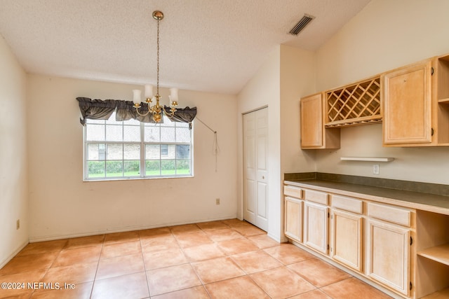 kitchen with light tile patterned flooring, decorative light fixtures, vaulted ceiling, and an inviting chandelier