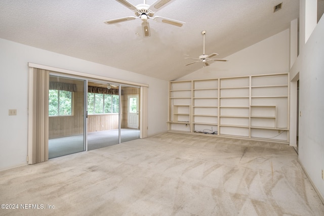 interior space with light carpet, vaulted ceiling, a textured ceiling, and ceiling fan