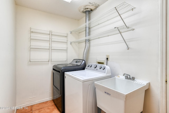 laundry area with washer and dryer, tile patterned floors, sink, and a textured ceiling