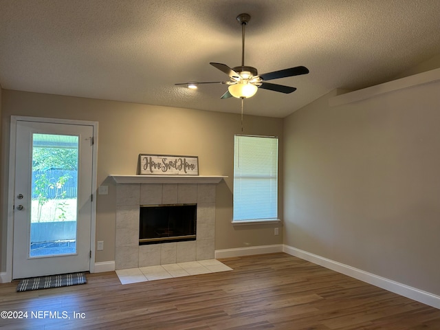 unfurnished living room featuring a fireplace, a textured ceiling, hardwood / wood-style flooring, and ceiling fan