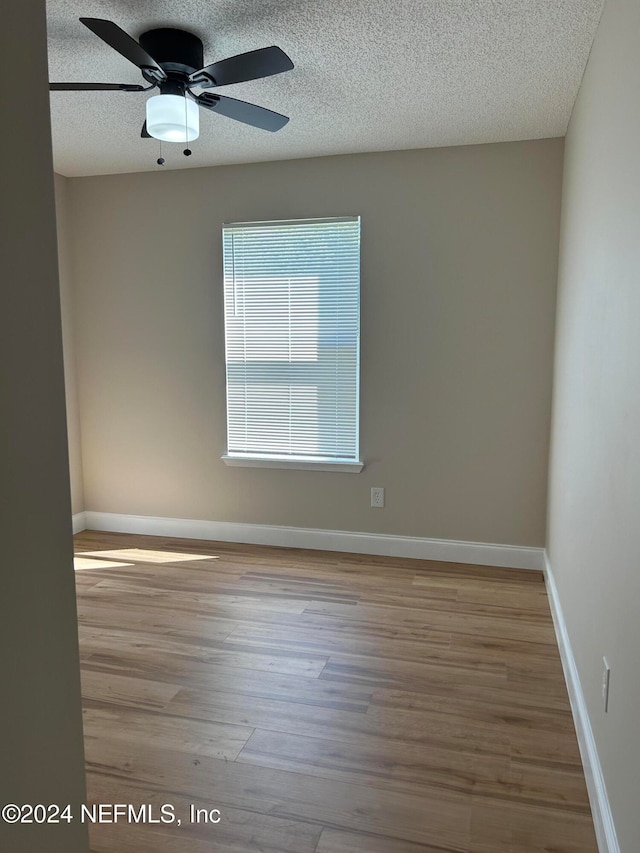 empty room with light hardwood / wood-style flooring, ceiling fan, and a textured ceiling