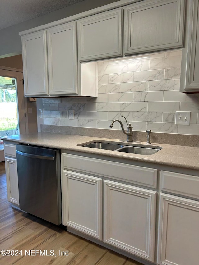 kitchen featuring white cabinets, light wood-type flooring, stainless steel dishwasher, and sink