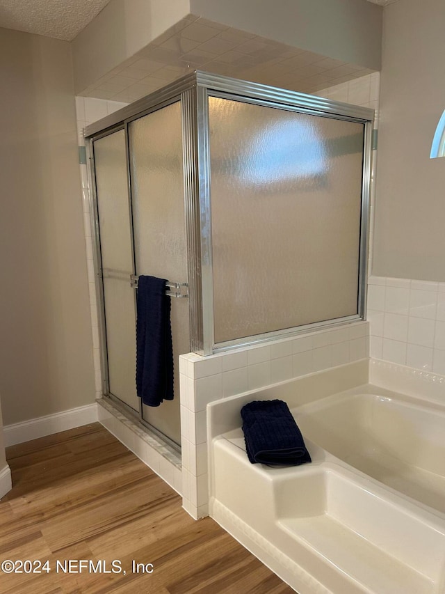 bathroom featuring plus walk in shower, hardwood / wood-style floors, and a textured ceiling