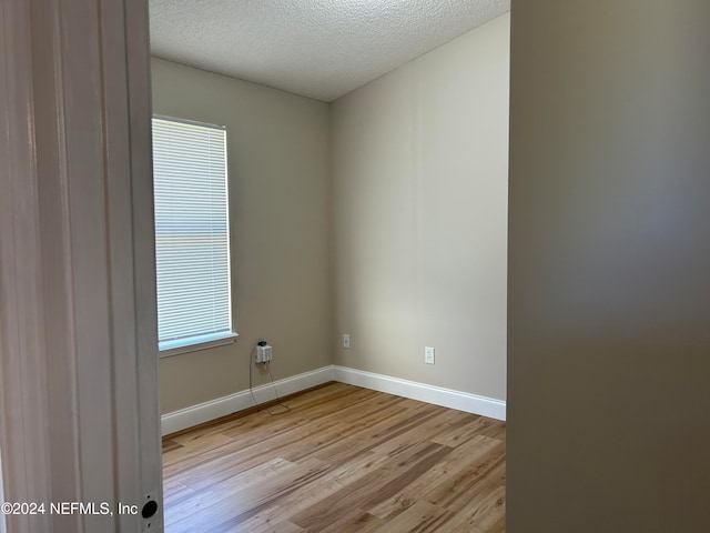 empty room with a textured ceiling and light wood-type flooring