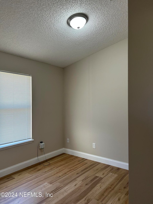 unfurnished room featuring a textured ceiling and light hardwood / wood-style floors