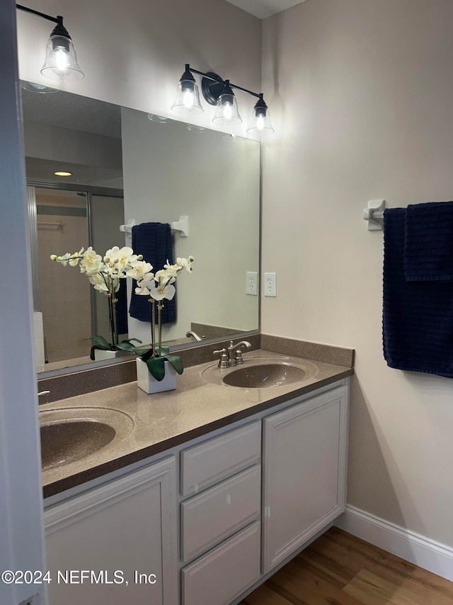 bathroom with hardwood / wood-style floors, vanity, and an enclosed shower