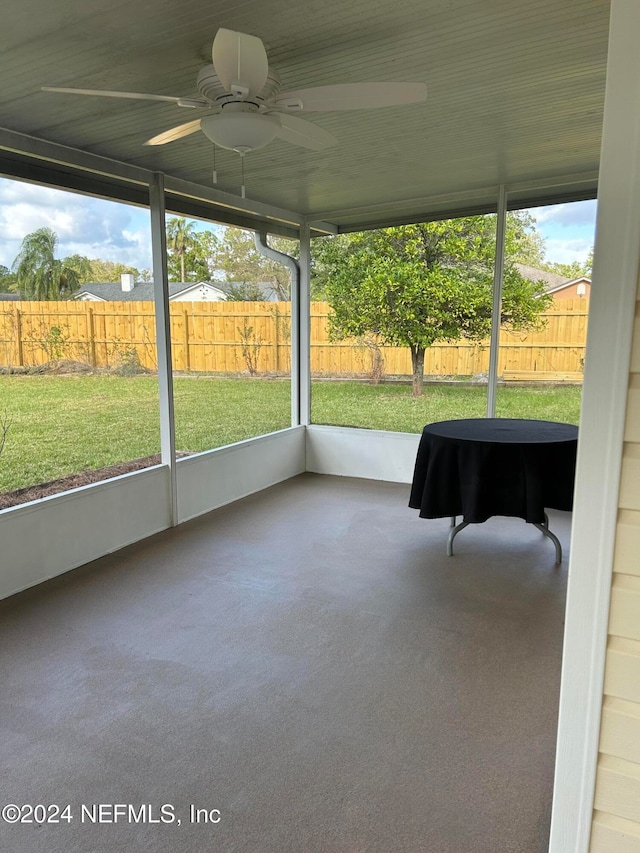 unfurnished sunroom featuring ceiling fan and plenty of natural light