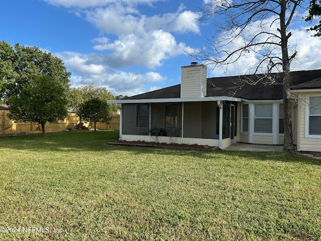 rear view of house with a lawn and a sunroom