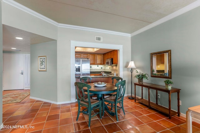 dining space with crown molding, sink, and tile patterned flooring