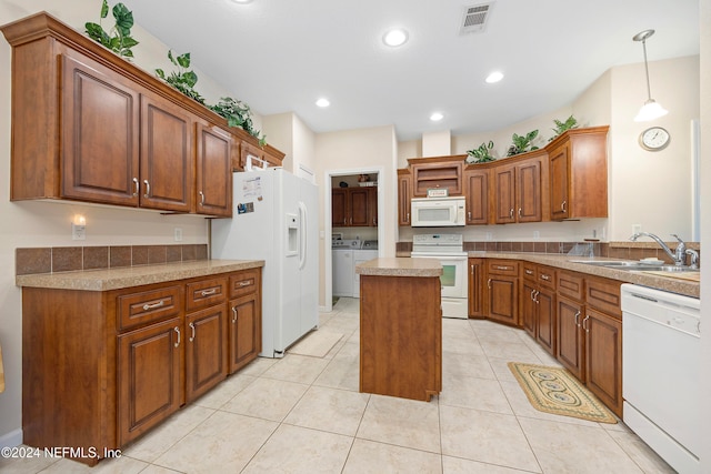 kitchen with white appliances, independent washer and dryer, sink, hanging light fixtures, and a center island