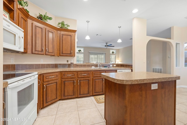 kitchen with a kitchen island, ceiling fan, white appliances, sink, and light tile patterned floors