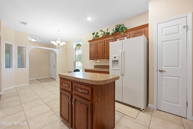 kitchen with white fridge with ice dispenser, decorative light fixtures, light tile patterned floors, and a center island