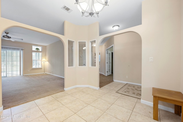 empty room featuring light colored carpet and ceiling fan with notable chandelier