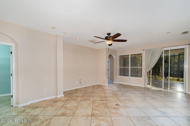 spare room featuring ceiling fan, light tile patterned flooring, and a textured ceiling