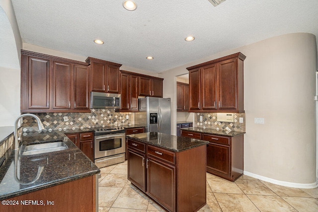 kitchen featuring stainless steel appliances, sink, a center island, dark stone countertops, and light tile patterned floors