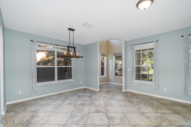 unfurnished dining area with a textured ceiling and an inviting chandelier