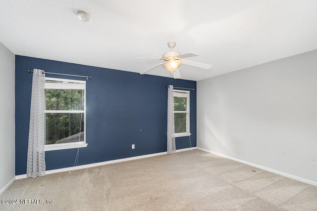 carpeted spare room with a textured ceiling and ceiling fan