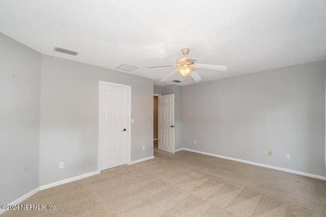 empty room featuring light colored carpet, ceiling fan, and a textured ceiling