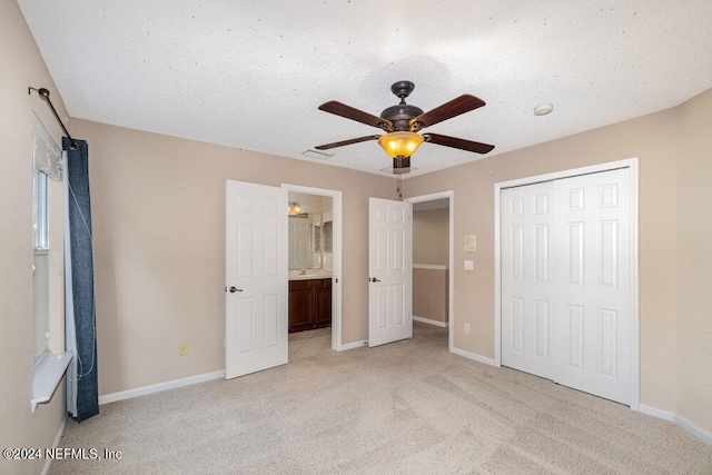 unfurnished bedroom featuring light colored carpet, ceiling fan, a textured ceiling, and a closet