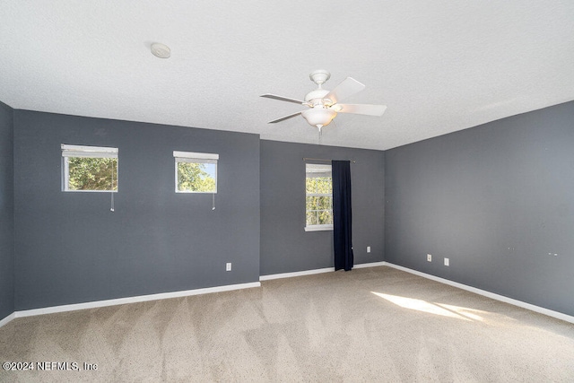 carpeted spare room featuring a textured ceiling and ceiling fan