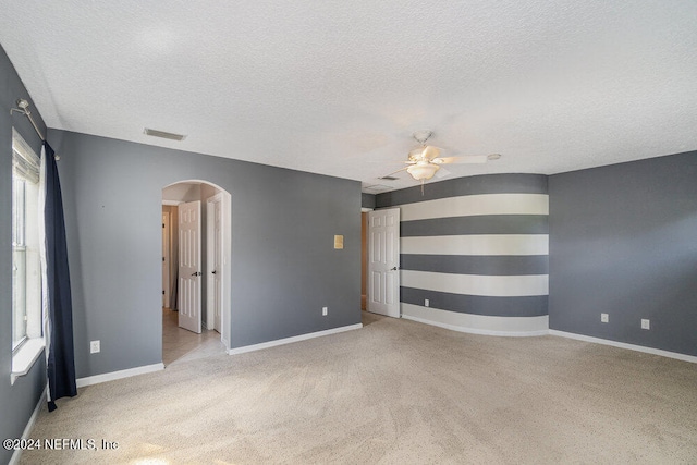 interior space with a textured ceiling, ceiling fan, and light colored carpet