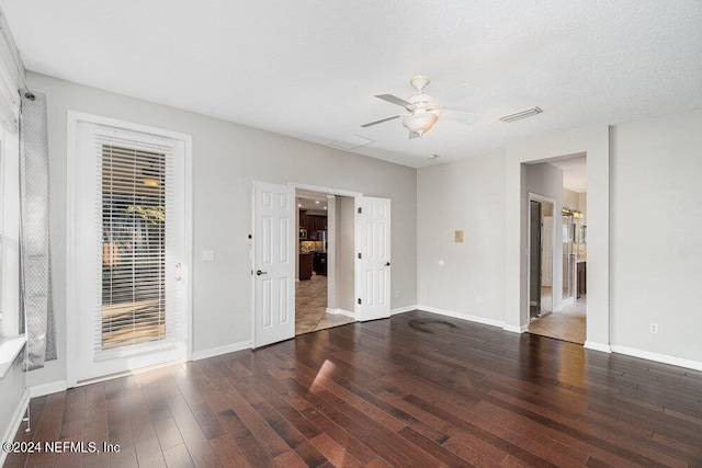 empty room featuring a textured ceiling, ceiling fan, and dark wood-type flooring