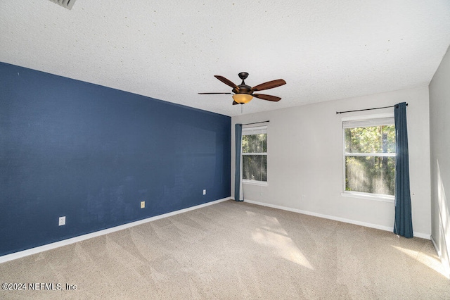 unfurnished room featuring a wealth of natural light, a textured ceiling, ceiling fan, and carpet