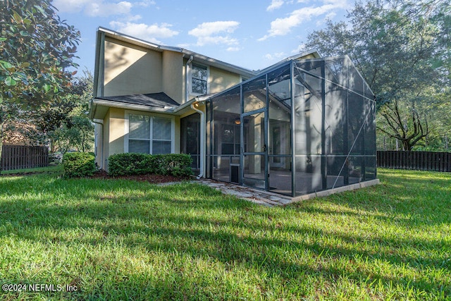 back of house with glass enclosure and a lawn