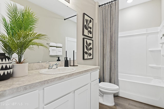 full bathroom featuring wood-type flooring, shower / bath combo with shower curtain, vanity, and toilet