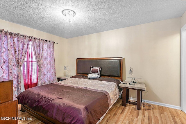 bedroom featuring light hardwood / wood-style flooring and a textured ceiling