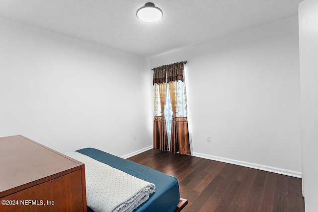 bedroom featuring a textured ceiling and dark wood-type flooring