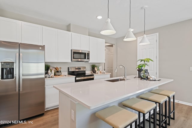 kitchen featuring an island with sink, decorative light fixtures, appliances with stainless steel finishes, and sink