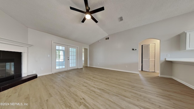 unfurnished living room featuring lofted ceiling, ceiling fan, french doors, and light hardwood / wood-style flooring