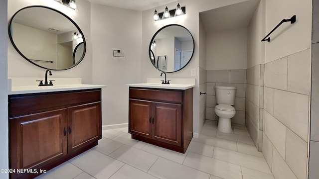 bathroom featuring tile patterned flooring, tile walls, vanity, and toilet