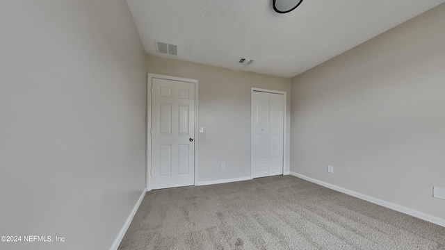 unfurnished bedroom with baseboards, visible vents, carpet floors, a closet, and a textured ceiling