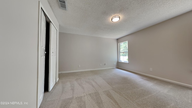 unfurnished bedroom featuring light carpet, a textured ceiling, and a closet