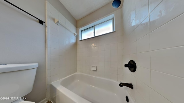 bathroom featuring tiled shower / bath, a textured ceiling, and toilet